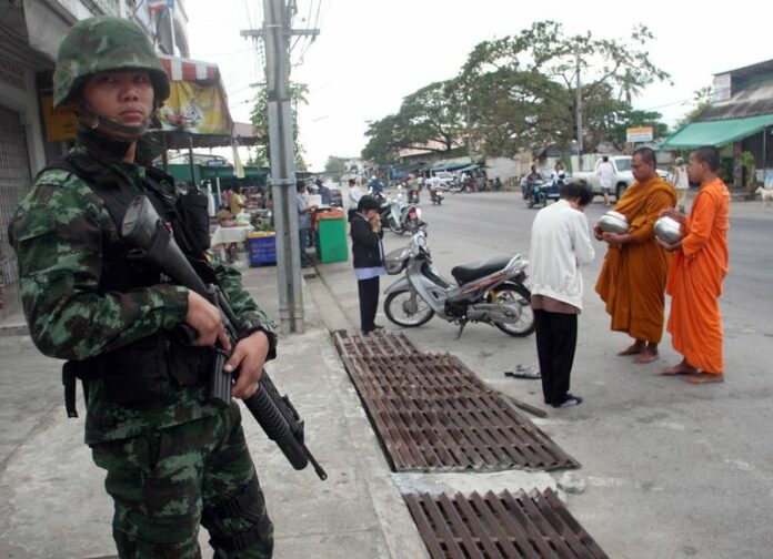 A Thai soldier provides security as villagers offer food to Buddhist monks in Pattani, southern Thailand, 08 March 2011. EPA/ABDULLAH WANGNI<br />