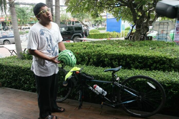 Thitiwat Rongthong, 25-year-old front man of The Darkest Romance, holds the helmet he says kept an attacker from slashing his head.