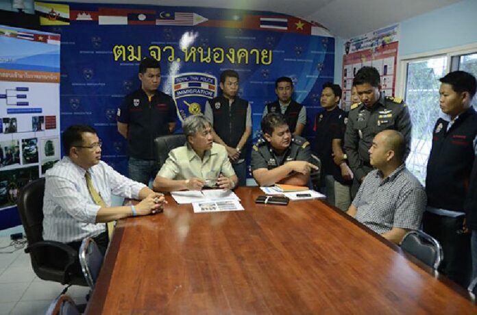 Korean-American Lee Isaac Byundo sits on the right at a police news conference Tuesday in Nong Khai province.