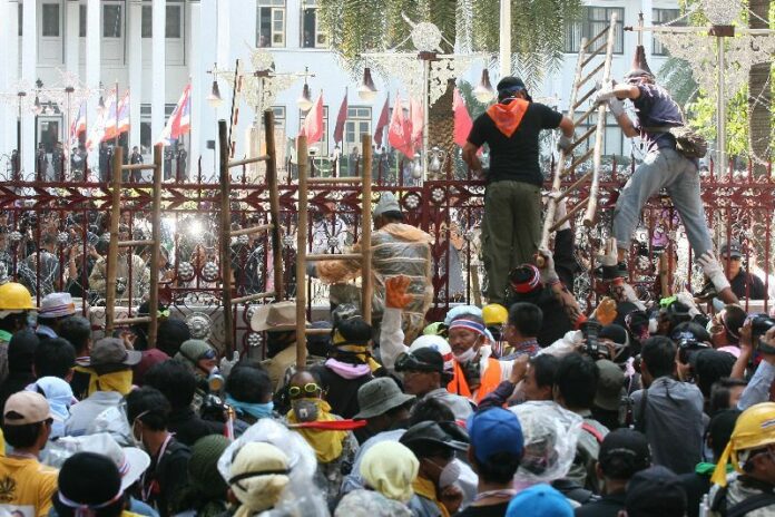 Anti-government protesters attempting to climb over the fence of Royal Thai Police headquarters in Bangkok in this 4 December, 2013, file photo.