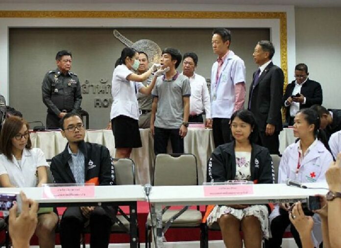 A police forensic technician takes a swab from the cheek of Warot Toovichian at a 30 Oct. news conference in Bangkok.