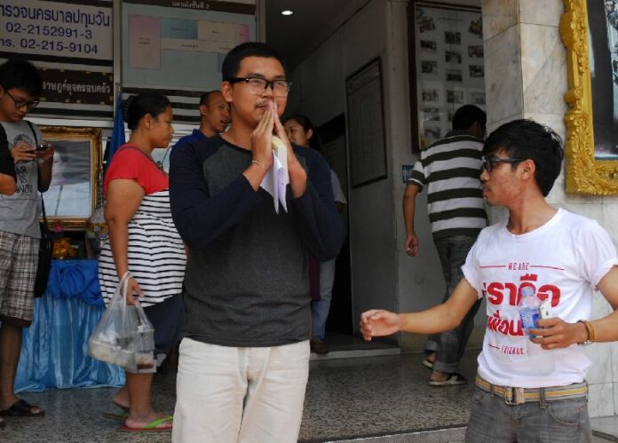 Taken into custody the day before at Don Mueang Airport, Songtham Kaewpanpruek greets supporters upon his release Sunday from the Pathumwan Police Station.