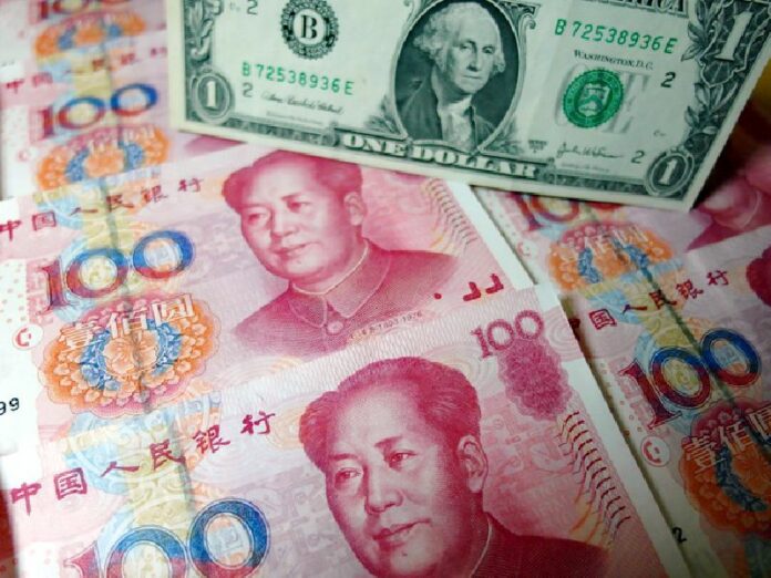 Yuan banknotes and US dollars are seen on a table in Yichang, central China's Hubei province on August 14, 2015. CHINA OUT AFP PHOTO