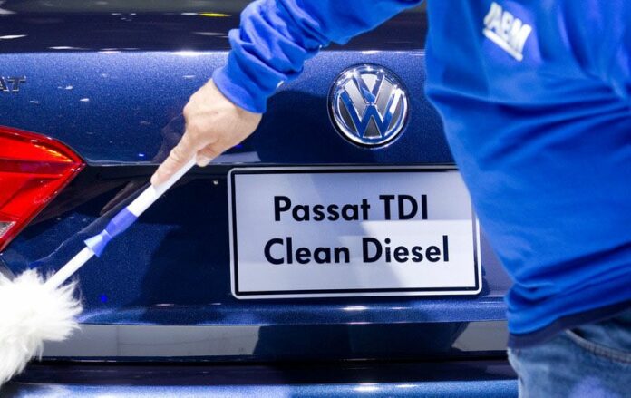 An archived photo shows a Volkswagen employee dusting a clean diesel Passat model in a showroom. Photo: Friso Gentsch/dpa