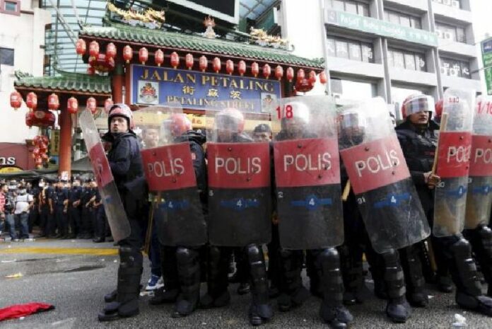 Riot police protect the entrance to Chinatown from 'Red Shirt' demonstrators during a rally to celebrate Malaysia Day and to counter a massive protest held over two days last month that called for Prime Minister Najib Razak's resignation over a graft scandal, in Malaysia's capital city of Kuala Lumpur on 16 Sept. Photo: Reuters / Olivia Harris