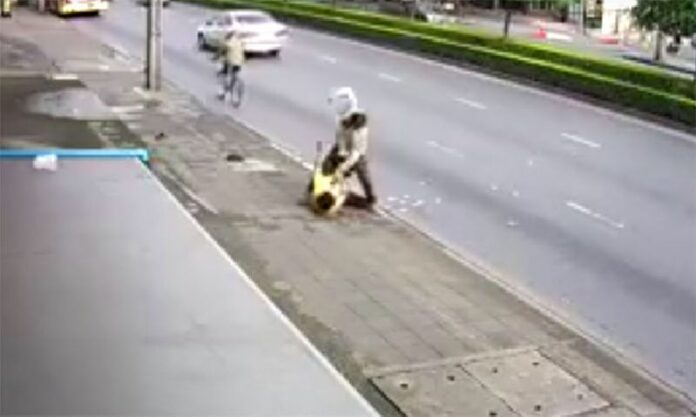 A man violently assaults a random passer-by Tuesday in Bangkok's Lat Phrao district in a still image from security camera footage.