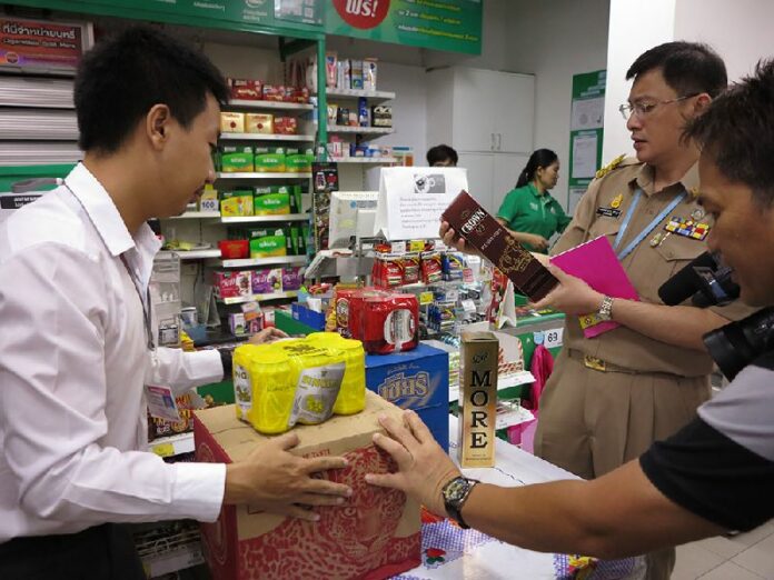 Samarn Footrakul, in uniform, raids a Tesco Lotus Express yesterday to look for brands running afoul of the latest alcohol restrictions he helped introduce.