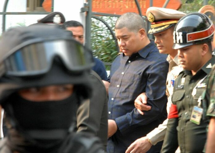 Police officers escort Police Maj. Prakrom Warunprapha to the martial court in Bangkok yesterday