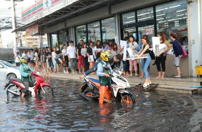 Commuters wait outside a 7-Eleven north of Bangkok in Rangsit, Pathum Thani, during April flooding.
