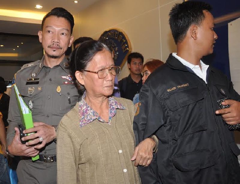 Juree Jan-ngam is escorted by officers Tuesday at the Crime Suppression Division in Bangkok.