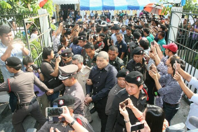Police officers escort policeman Prakrom Warunprapha (in black) on Oct. 21 to the martial court in Bangkok. Two more police officers will be charged with lese majeste, a police commander says today.