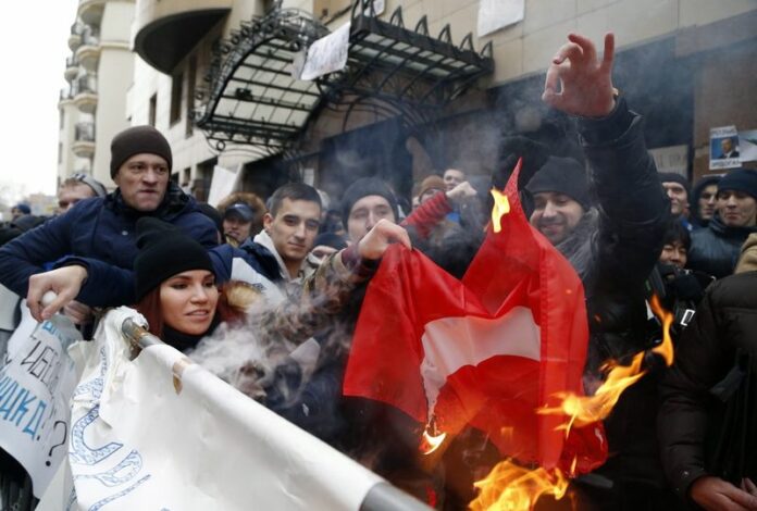 Russians burn a Turkish flag in front of the Turkish embassy Wednesday in Moscow.Photo: Maxim Shipenkov / EPA<br />