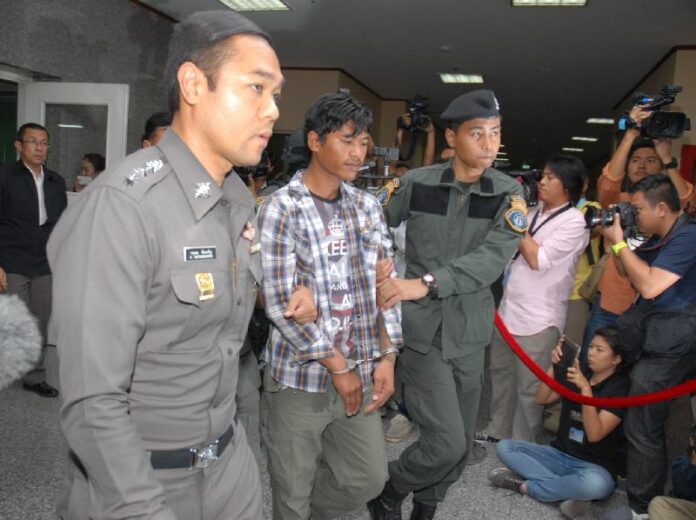 Nattapol Nawanle is led through police headquarters in Bangkok today. He is accused of being part of a radical Redshirt cell plotting to disrupt the country and possibly assassinate junta chairman Prayuth Chan-ocha.