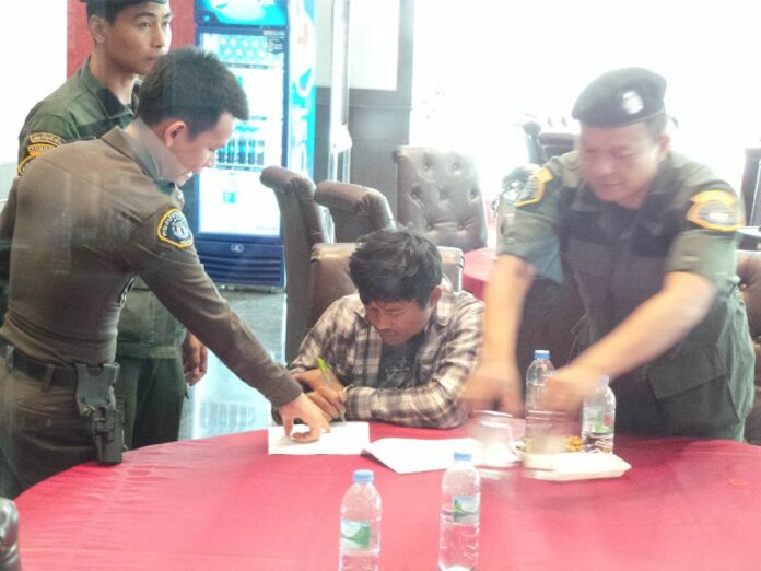 Nattapol Nawanle signs a document at police headquarters in Bangkok today. He is accused of being part of a radical Redshirt cell plotting to disrupt the country and possibly assassinate junta chairman Prayuth Chan-ocha.