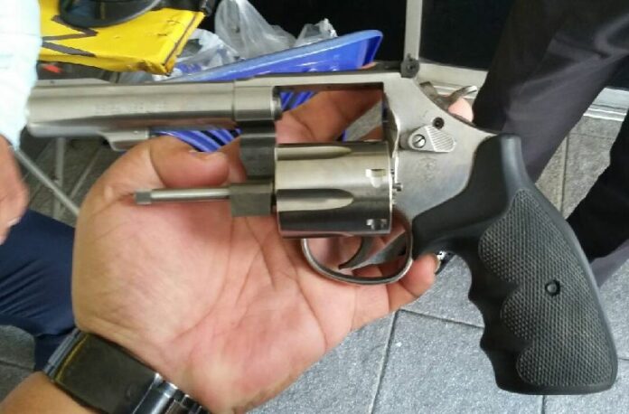 A Pattaya police officer holds the .38 handgun allegedly used Monday by G4S security guard Natthapong Konchanthet to threaten a man for parking his motorcycle on bank property.