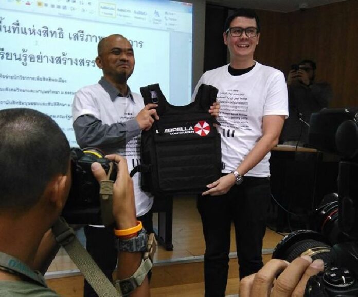 Rangsiman Rome, a student member of the New Democracy Movement at right, presents a prop bullet- and possibly zombie-proof vest to Anusorn Unno, dean of Thammasat University’s Faculty of Sociology and Anthropology on Dec. 4 at Thammasat University. Photo: New Democracy Movement / Facebook<br />