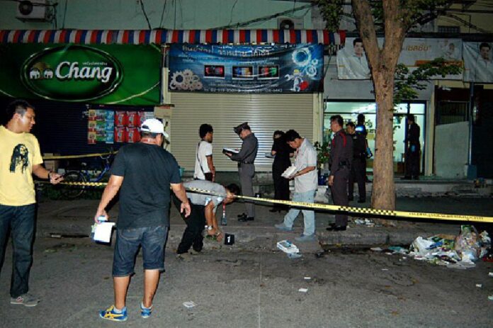 Police inspect the scene Monday evening on Soi Suan Siam 15 where three people were shot dead, reportedly over a parking conflict.