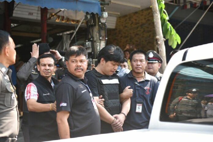 Triple-homicide suspect Thossaporn Pitakwattanon, handcuffed at center, is escorted by police to a ‘reenactment’ of his alleged crime Wednesday in Bangkok.