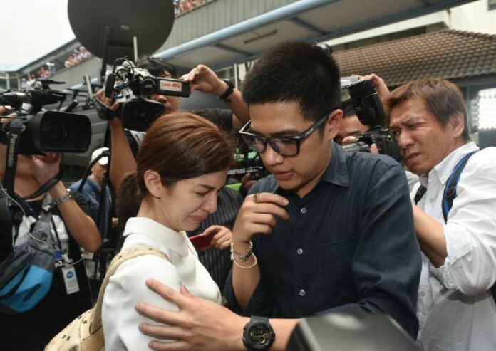 Vanda 'Bow' Sahawong and Chawanan 'Pin' Sahawong, wife and brother of late actor Thrisadee 'Por' Sahawong, cringe from the media onslaught Tuesday outside Ramathibodi Hospital in Bangkok.