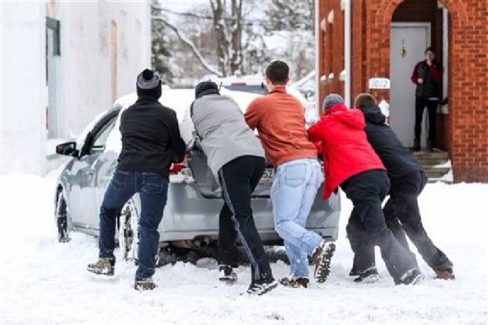 People push a car stuck in snow in Huntington, West Virginia, Saturday Jan.23, 2016. Photo: Sholten Singer / AP