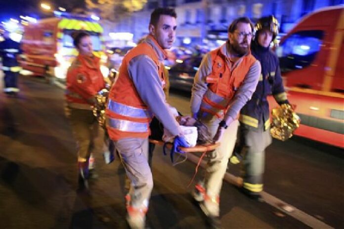 In this Nov. 13, 2015, file photo, a woman is evacuated from the Bataclan concert hall after gunmen attacked the venue in Paris. Photo: Thibault Camus / AP