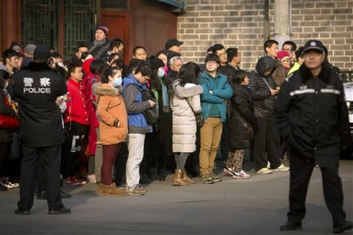 In this Jan. 1, 2016 file photo, Chinese policemen watch as depositors from Ezubao gather outside the State Bureau for Letters and Calls Reception Division office in Beijing. Photo: Mark Schiefelbein / AP