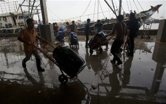 In this June 20, 2014 file photo, migrant workers unload frozen fish from a boat at a fish market in Samut Sakhon Province. Photo: Sakchai Lalit / AP