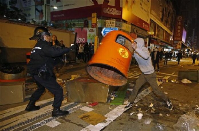 A rioter tries to throw a litter bin at police on a street in Mong Kok district of Hong Kong, Tuesday, Feb. 9, 2016. Photo: Kin Cheung / AP