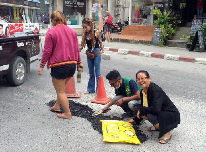 Souvenir merchant Samran Lungkum, at right, and Chaweng Beach locals come together Monday to repair their road. Photo: Samran Lungkum / Facebook