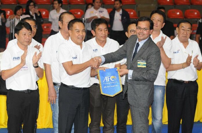 Somyot Poompunmuang, in a polo shirt, center left, is congratulated by an official from the Asian Football Confederation, in Bangkok, Feb. 11, 2016