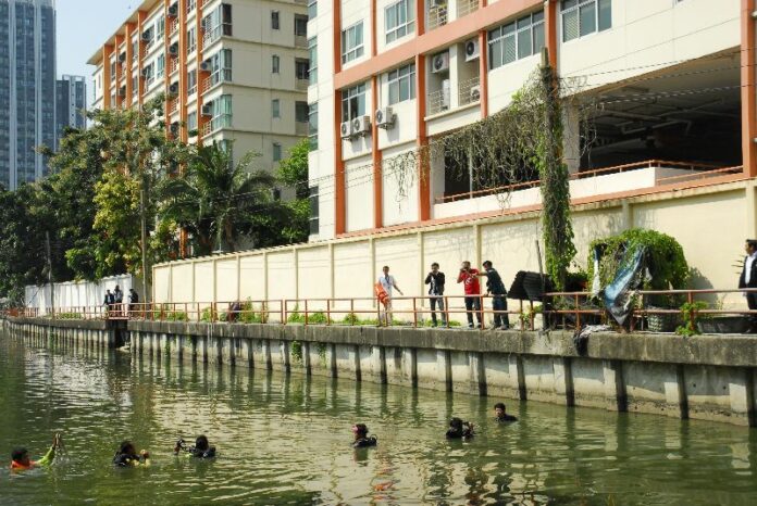 Officers on Tuesday inspect the canal behind PG Rama 9 Condominium where it is believed the murder suspect, Artur Segarra, disposed of the knives used in the murder and dismemberment of David Bernat.