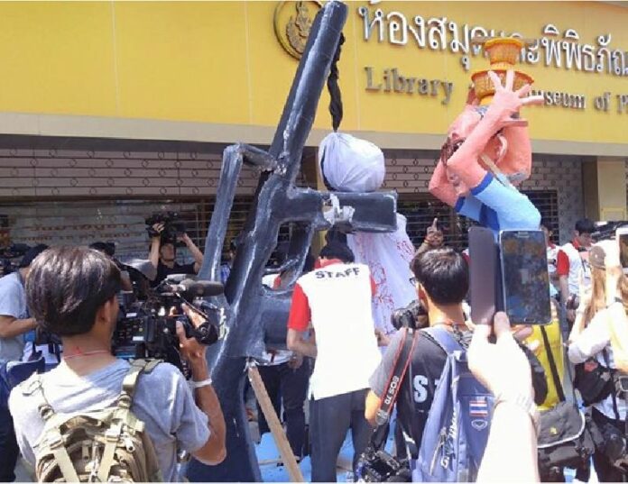 Thammasat university students remove a rifle from a float satirizing the junta-sponsored draft constitution Saturday at Bangkok’s National Stadium. Photo: Matichon