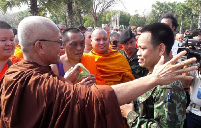 A monk and soldier speak Monday west of Bangkok at a Buddhist park in Nakhon Pathom province.