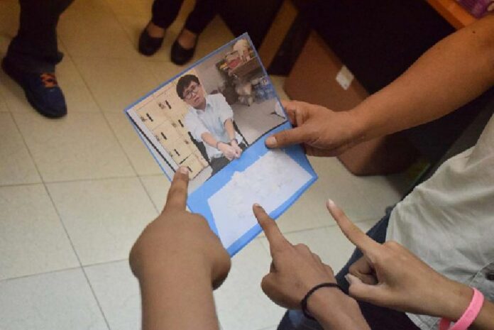 Accusing fingers are pointed toward a photograph of Chanabodin ‘Ja’ Nikulkan on Thursday at the Buppha Ram Police Station in western metro Bangkok.