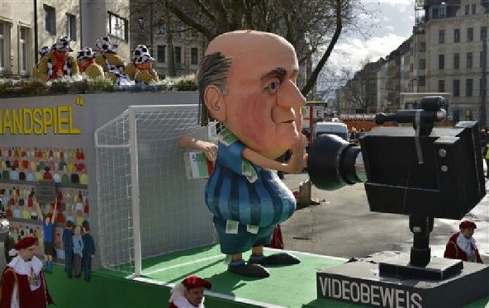 A carnival float depicting suspended FIFA president Sepp Blatter receiving money while he stands in a goal in front of a camera during the traditional carnival parade in Cologne, western Germany, Monday, Feb. 8, 2016. Photo: Martin Meissner/ Associated Press.