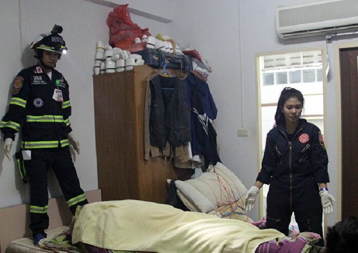 Rescue workers stand over the body of a 64-year-old Australian man found Tuesday night inside a room at the Grand Wana Hotel in Uttaradit province.