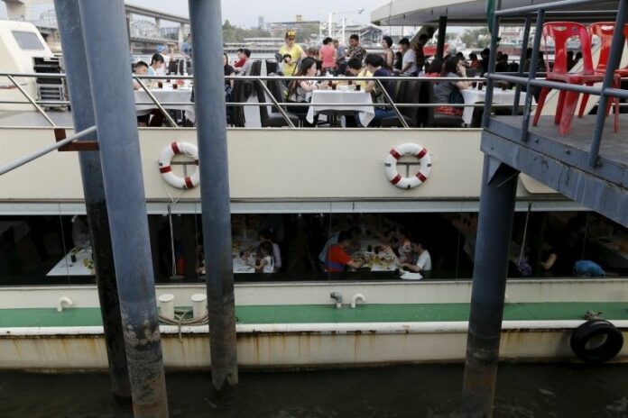 Chinese tourists dine on board a boat at a pier at Chao Phraya river in Bangkok Feb. 16, 2016. Photo: Jorge Silver / Reuters