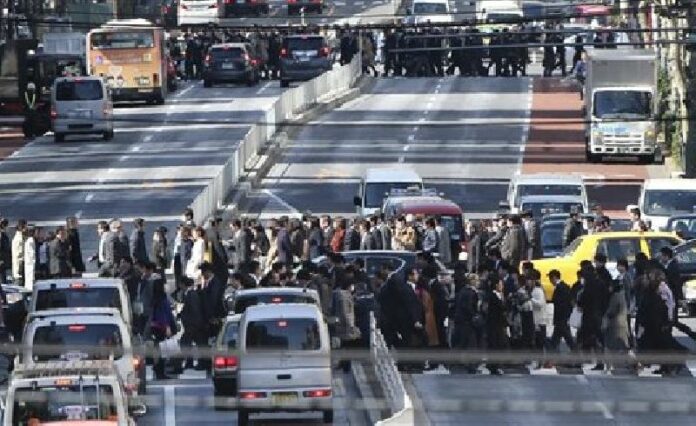 People cross crosswalks on a street in Tokyo, Friday, Feb. 26, 2016. Photo: Koji Sasahara / Associated Press