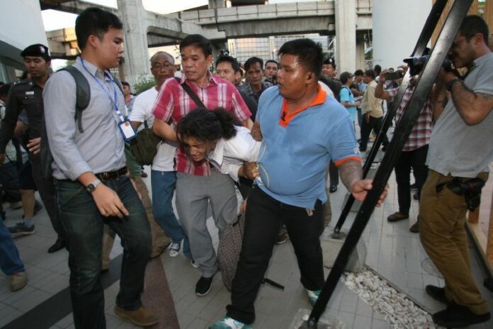 Security officers drag protesters away from a pro-democracy demonstration on the coup anniversary of May 22, 2015, in downtown Bangkok.