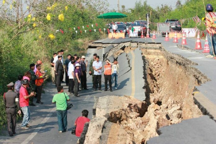 A crowd surveys a chasm Tuesday which opened in a road alongside a canal north of Bangkok in Pathum Thani.