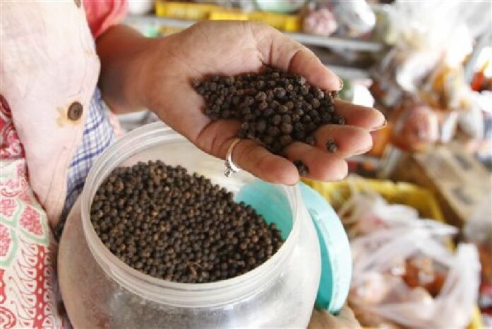 In this Tuesday, Mar. 1, 2016 photo, a vendor holds a handful of Kampot pepper at a market in Phnom Penh, Cambodia. Photo: Heng Sinith / Associated Press
