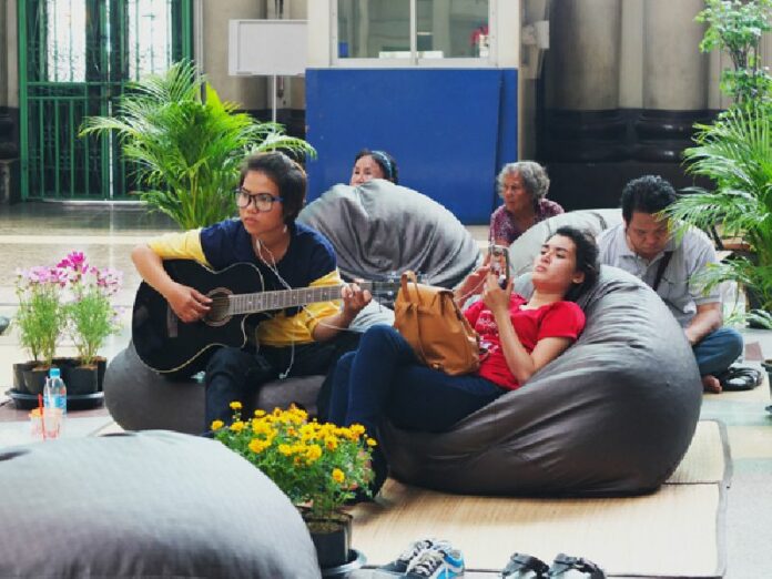 A passenger plays guitar while waiting for a delayed train Thursday at the Bangkok Railway Station.