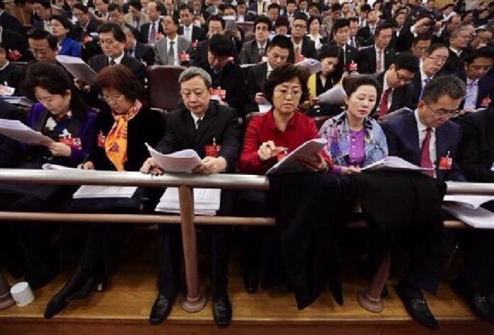 Delegates read the work report delivered by Chinese Premier Li Keqiang during the opening session of the annual National People's Congress at the Great Hall of the People in Beijing, Saturday, March 5, 2016. Photo: Andy Wong / Associated Press