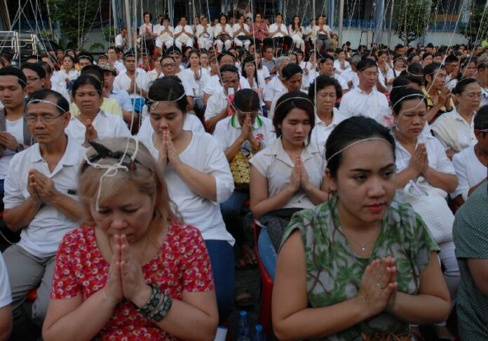 Worshipers linked through ‘sai sin’ to the chedi of Wat Traimit pray Sunday in Bangkok.