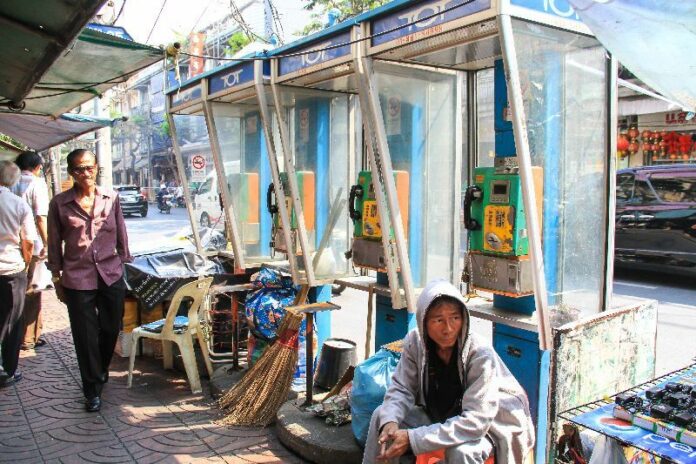 Vendors and street sweepers store their goods in phone stalls Thursday around Phadung Dao and Charoen Krung roads in Bangkok.
