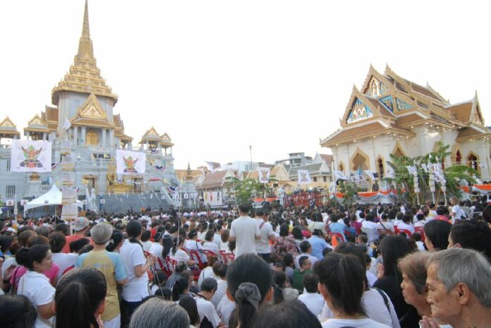 Worshipers linked through ‘sai sin’ to the chedi of Wat Traimit pray Sunday in Bangkok.