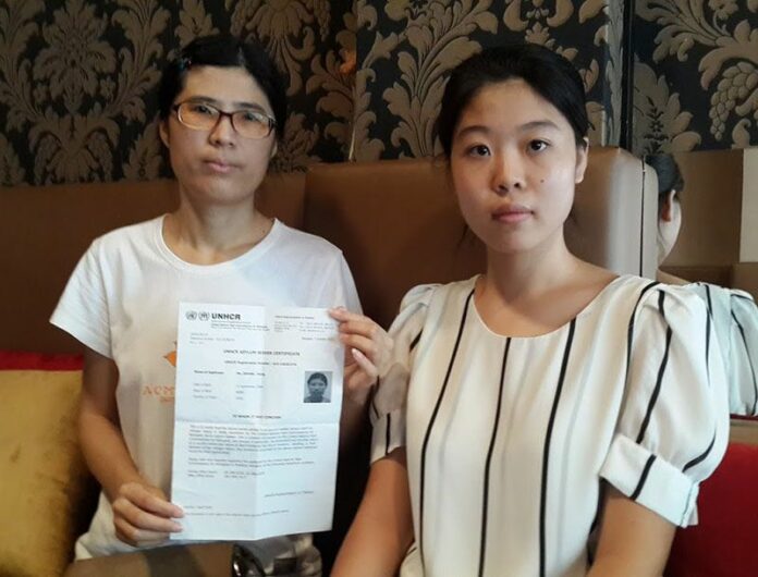 Lisa Zhang, at left, displays her certification as an asylum seeker alongside Amity Dong on Friday in Bangkok.