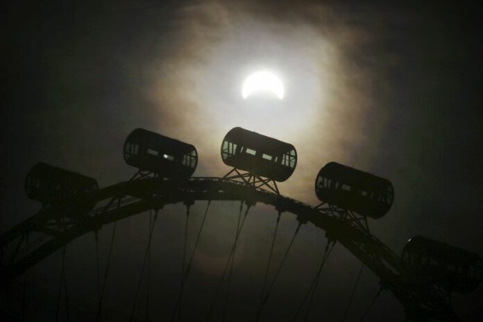 A partial solar eclipse is seen behind passenger capsules of the Singapore Flyer on Wednesday in Singapore. Photo: Wong Maye-E / Associated Press