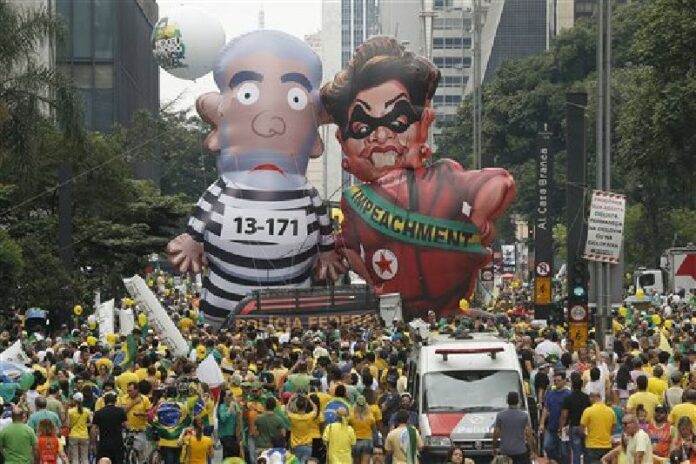 Demonstrators parade large inflatable dolls depicting Brazil's former President Luiz Inacio Lula da Silva in prison garb and current President Dilma Rousseff dressed as a thief, with a presidential sash that reads "Impeachment," in Sao Paulo, Brazil, Sunday, March 13, 2016. Photo: Andre Penner / Associated Press