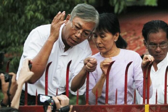 <br />In this Nov. 13, 2010, photo, Myanmar's pro-democracy leader Aung San Suu Kyi, center, speaks with aide Htin Kyaw, left, as she addresses her supporters from the front gates of her home after her release from house arrest in Yangon, Myanmar. Photo: Gemunu Amarasinghe / Associated Press.
